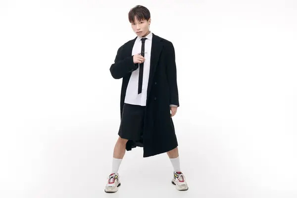 Jovem ásia homem no preto casaco e elegante roupa poses confiantemente contra um simples pano de fundo. — Fotografia de Stock
