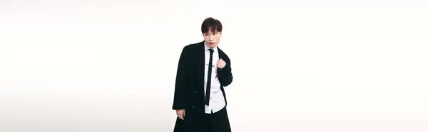 Un joven y encantador hombre asiático posa con confianza en un atuendo elegante sobre un fondo limpio. - foto de stock
