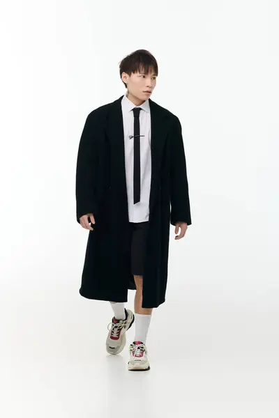 A young, handsome Asian man in a modern outfit radiates confidence in a minimalist space. — Stock Photo