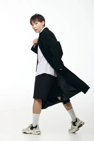 Young handsome asian man confidently walks in a minimalist setting, displaying his unique style. — Stock Photo