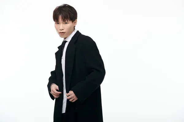 Um jovem e atraente macho asiático exala confiança em um casaco preto elegante enquanto posando elegantemente. — Fotografia de Stock
