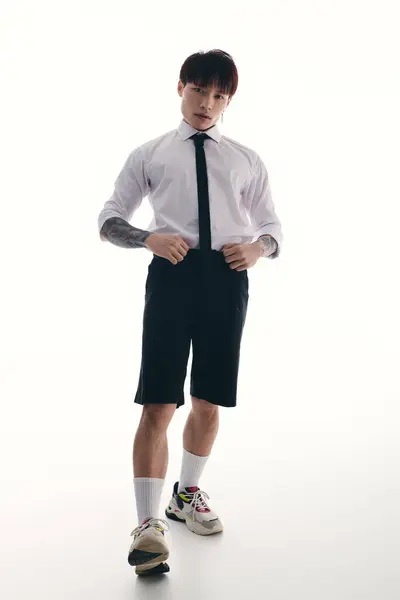 A handsome young asian man stands confidently, showcasing a trendy outfit with a modern flair. — Stock Photo