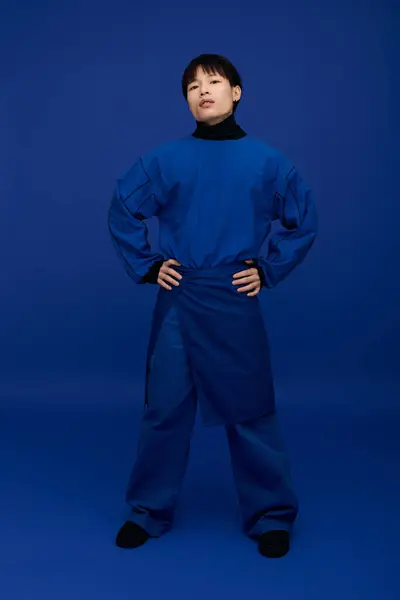Confident young Asian man poses with hands on hips, flaunting his striking blue outfit. — Stock Photo