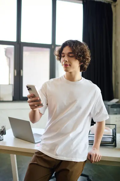 A young and attractive man checks his smartphone while standing in a stylish office space. — Stock Photo