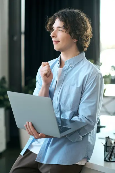 Un hombre joven y atractivo en un ambiente de oficina elegante se involucra en un trabajo reflexivo con una computadora portátil. — Stock Photo