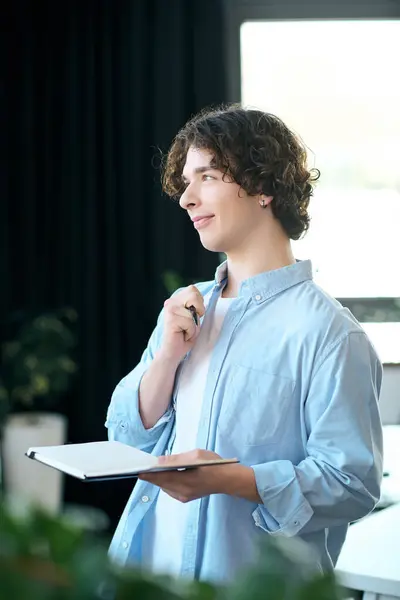 Attractive young man deep in thought in a sleek office environment clutching a notebook — Stock Photo