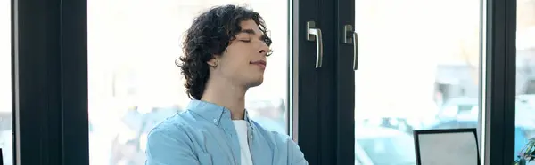 Joven guapo se relaja con los ojos cerrados en un espacio de oficina contemporáneo durante las horas de trabajo. - foto de stock