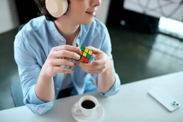 In a contemporary office space, a handsome young man savors coffee and solves a colorful puzzle. — Stock Photo