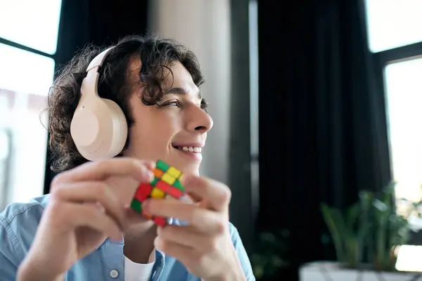Jovem profissional confiante resolve um quebra-cabeça colorido e ouve música para uma vibração relaxada. — Fotografia de Stock
