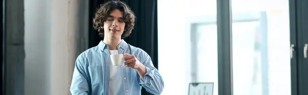 Attractive young man takes a moment to savor his coffee in a stylish office setting. — Stock Photo