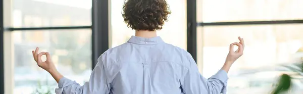 Handsome young man with curly hair engages in mindful meditation at work during a quiet moment. — Stock Photo