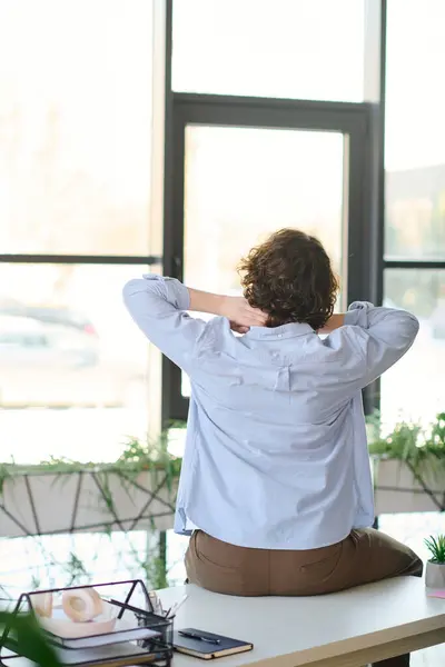 Bright office space captures a young man taking a moment to relax, reflecting on his workday. — Stock Photo