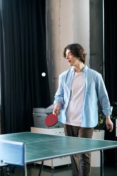 Handsome young man engages in table tennis at his office, enjoying a playful moment between tasks. — Stock Photo