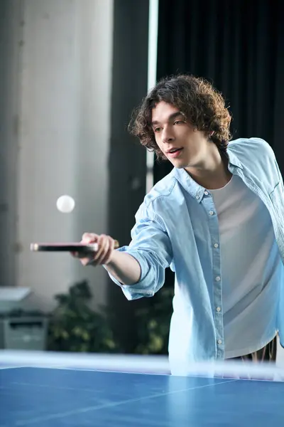 A handsome young man focuses intently while playing table tennis in an office setting. — Stock Photo