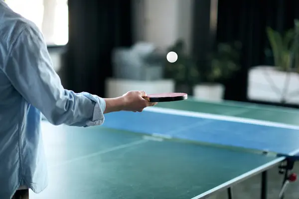 Handsome young man focuses on the ping pong ball while preparing for a game in a sleek office space — Stock Photo