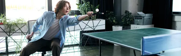 A young handsome man passionately plays table tennis in a stylish office during his break. — Stock Photo