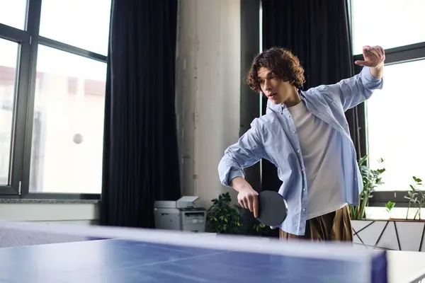 A good looking young man is engaged in playing table tennis, showcasing his skills and enjoyment. — Stock Photo