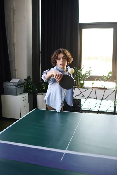 A young man plays table tennis in a lively office, showing skill and energy. — Stock Photo