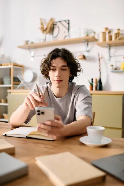 Giovane uomo con i capelli ricci si concentra su smartphone mentre seduto a una scrivania elegante ufficio. — Foto stock
