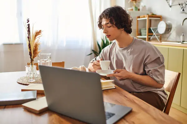 Handsome young man savors a cup of coffee at a stylish workspace with natural light streaming in. — Stock Photo