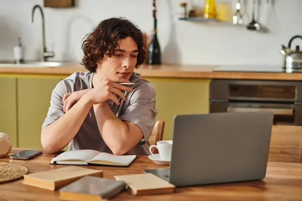 Focused giovane uomo si impegna con il suo computer portatile mentre seduto in un elegante ufficio di lavoro — Foto stock