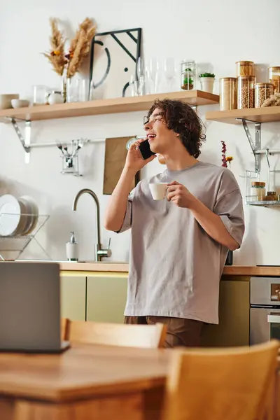 Un uomo giovane e attraente si impegna in una telefonata in un ufficio elegante sorseggiando un caffè. — Foto stock