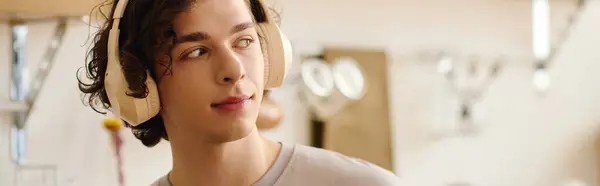 Handsome young man wearing headphones smiles as he works in a bright and stylish office space — Stock Photo