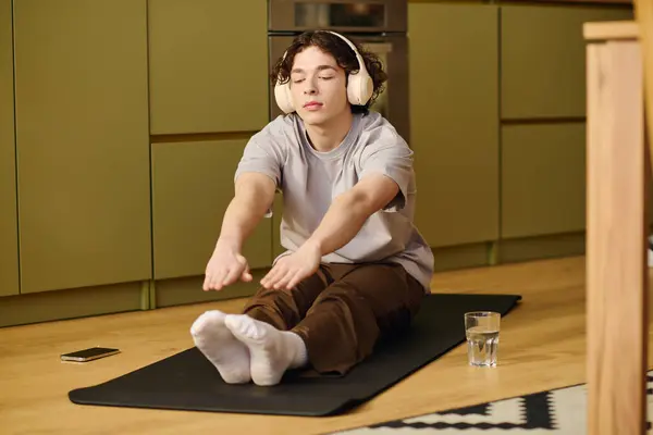 Joven enfocado se dedica al yoga se estira sobre una estera en una cocina luminosa y contemporánea. - foto de stock