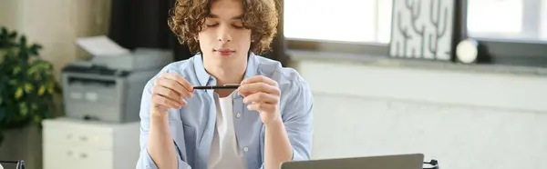Young man with curly hair thinks with a pen in a modern, bright office. — Stock Photo
