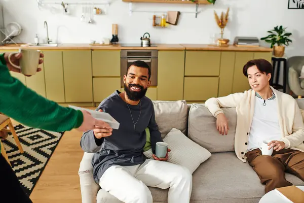 Young handsome men enjoy a lively discussion while seated in a stylish, cozy living room. — Stock Photo