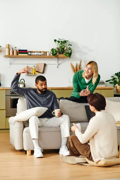 Three handsome young men engage in lively conversation during a casual book club meeting at home. — Stock Photo