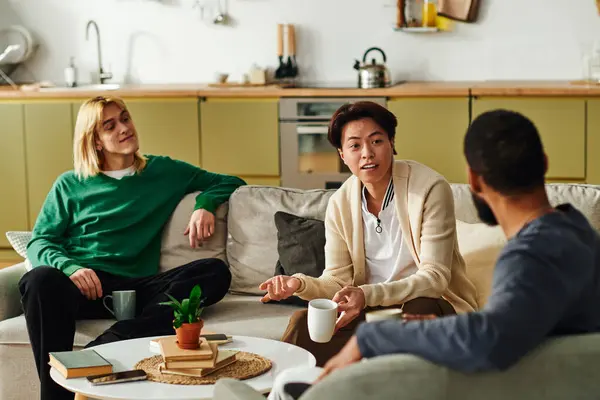 Three young men bond over literature and conversation in their stylish and comfortable living room. — Stock Photo
