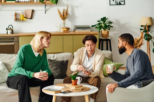 Tres jóvenes guapos comparten ideas y disfrutan de una acogedora reunión en su club de libros caseros. - foto de stock