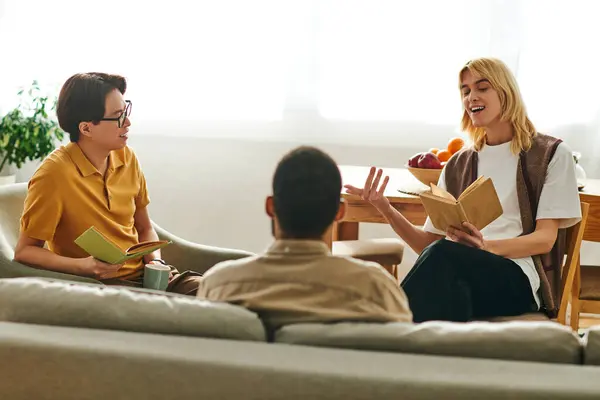 Three young, stylish men enjoy an animated discussion while sharing their favorite books at home. — Stock Photo