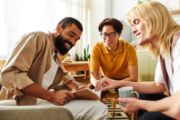 Three diverse young men bond over books and ideas during a casual home book club. — Stock Photo