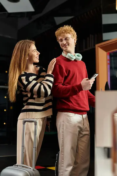 Ein junges Paar an einer Hotelrezeption strahlt Liebe aus, als sie einen freudigen Moment beim Einchecken teilen. — Stockfoto