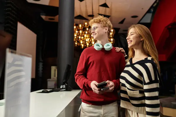 Una pareja feliz se encuentra en el vestíbulo de un hotel, irradiando amor y energía juvenil. - foto de stock