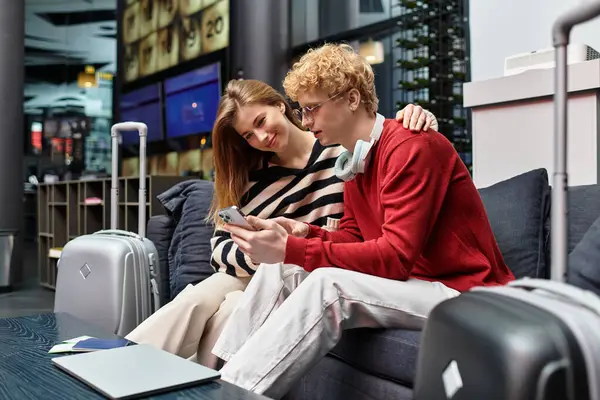 A young couple shares a joyful moment on a cozy couch in a modern hotel lounge, immersed in love. — Stock Photo