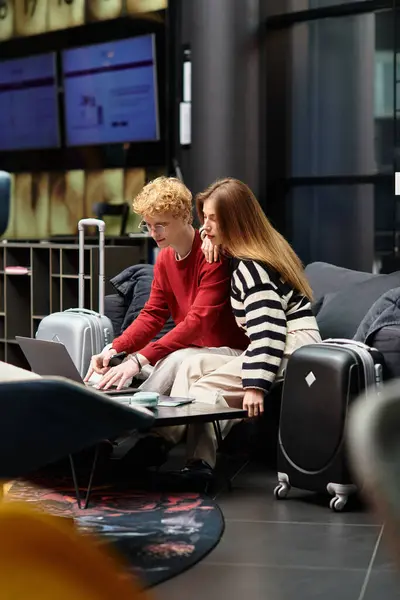 A young couple sits together at a modern hotel, collaborating on travel plans with enthusiasm. — Stock Photo