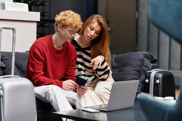 A loving couple sits on a comfortable couch at a hotel, sharing travel plans and smiles together. — Stock Photo