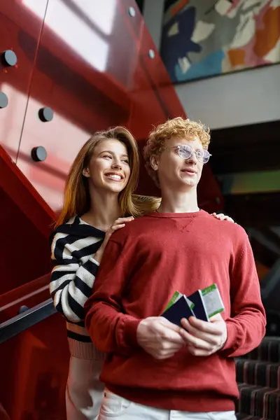 A loving young couple enjoys each others company as they enter a colorful hotel, radiating joy. — Stock Photo