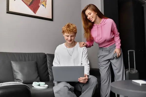 A young couple bonds over travel plans, joyfully enjoying each others company on the couch. — Stock Photo