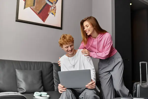 Loving couple enjoys quality time as they engage with a laptop in their cozy hotel accommodation. — Stock Photo
