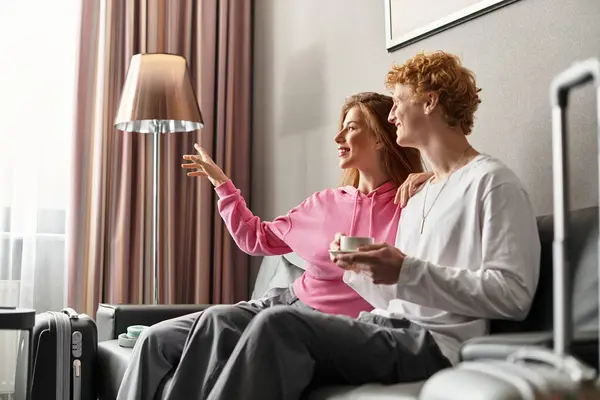 In a welcoming hotel room, a young couple enjoys each others company, embracing warmth and joy. — Stock Photo