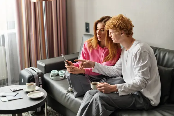 Young couple relaxes in hotel room, sharing laughs and affection over coffee and conversation. — Stock Photo