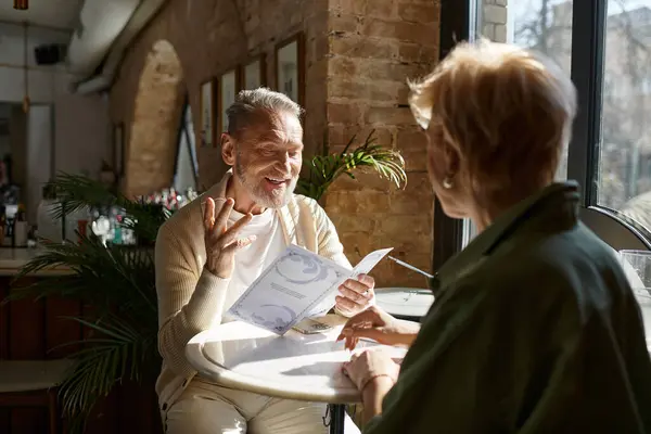 Una encantadora pareja disfruta de una comida juntos, comprometidos en una cálida conversación y risas. - foto de stock