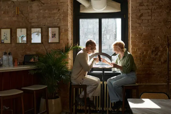 A middle-aged couple enjoys a delightful meal together in a charming cafe. — Stock Photo