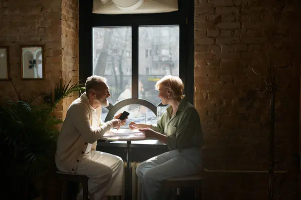 Middle aged couple shares laughter and smiles during their romantic cafe date, enveloped by charm. — Stock Photo