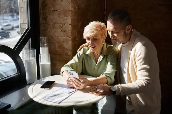 Middle aged couple enjoys each others company while sharing laughter and a smartphone. — Stock Photo