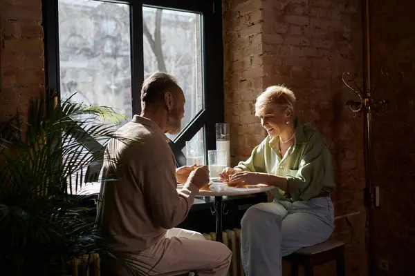 A middle aged couple shares laughter and conversation during a romantic evening at a cafe. — Stock Photo